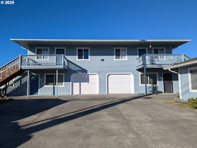 view of front of house with an attached garage, driveway, a balcony, and stairs