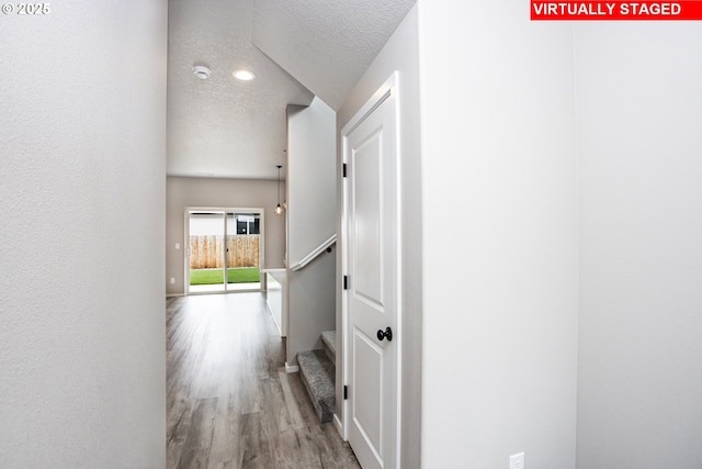 corridor featuring stairs, wood finished floors, and a textured ceiling