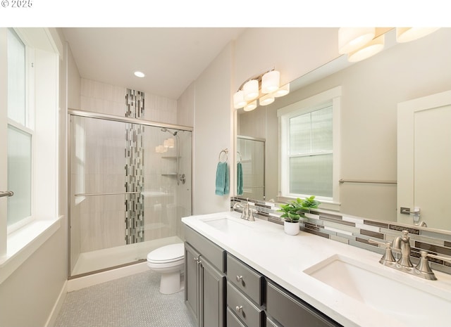 full bath featuring toilet, a sink, double vanity, and a stall shower