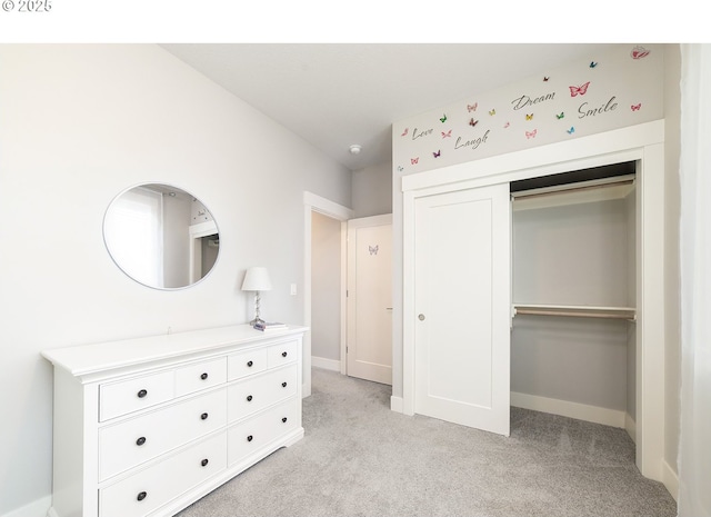 bedroom featuring a closet, baseboards, and light carpet