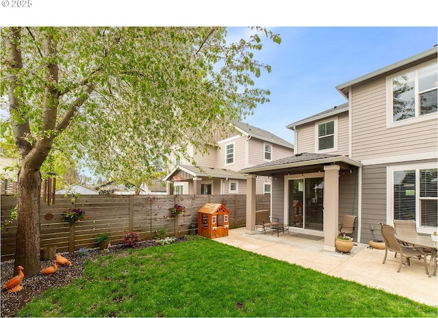 rear view of house with a fenced backyard, a patio area, and a lawn