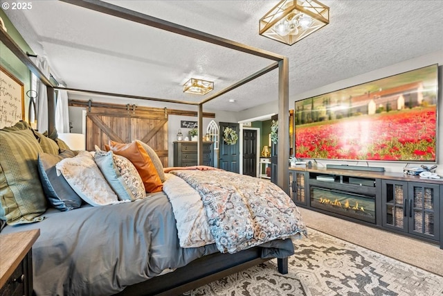 carpeted bedroom featuring a barn door and a textured ceiling