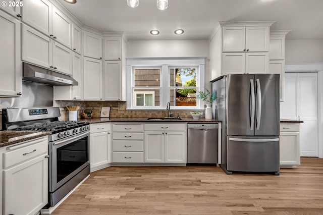 3136 NE 41st Ave, Portland, OR 97212 - kitchen featuring appliances with stainless steel finishes, a sink, under cabinet range hood, decorative backsplash, and white cabinets
