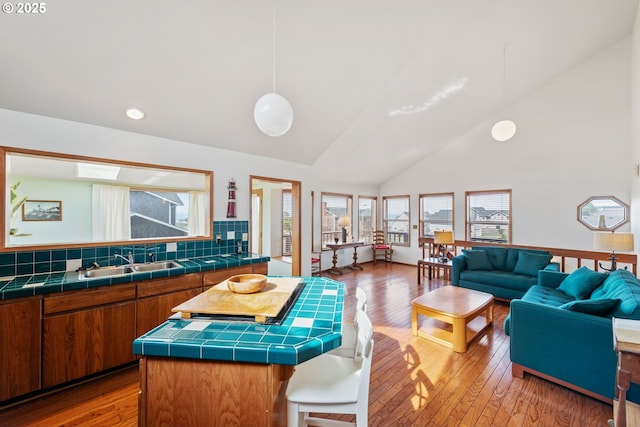 kitchen with light wood-style flooring, open floor plan, a sink, and tile countertops