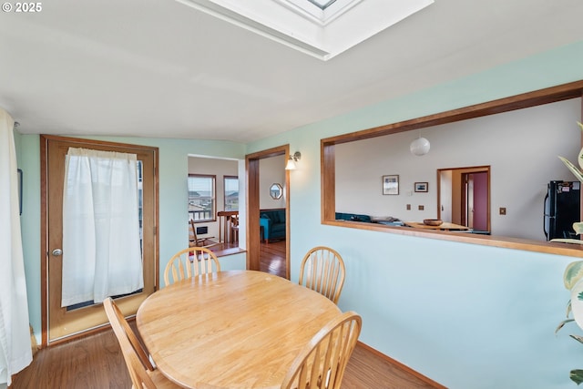 dining space with a skylight and wood finished floors