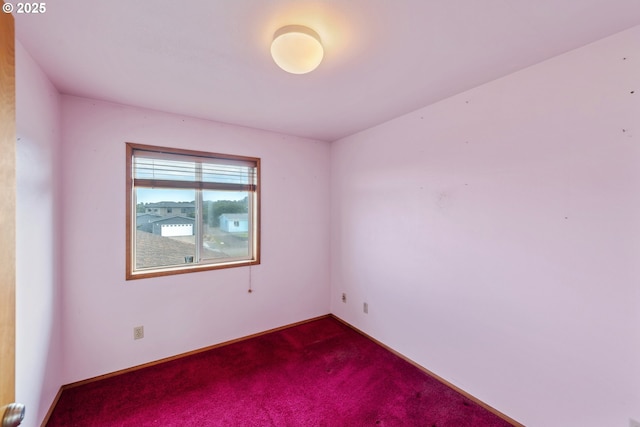 empty room with dark colored carpet and baseboards