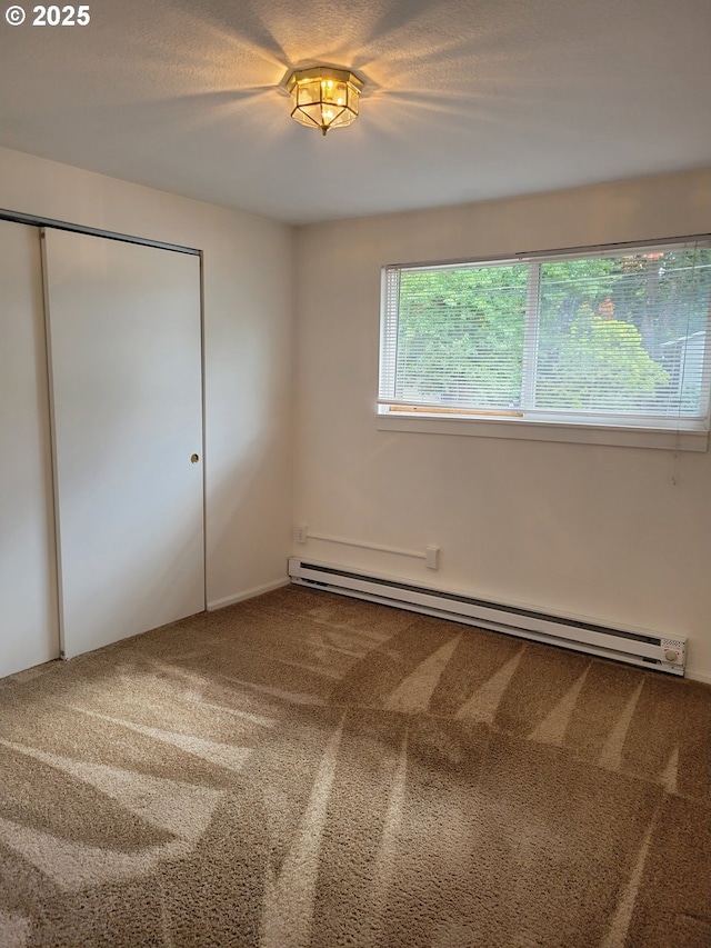 unfurnished bedroom with carpet flooring, a closet, and a baseboard heating unit