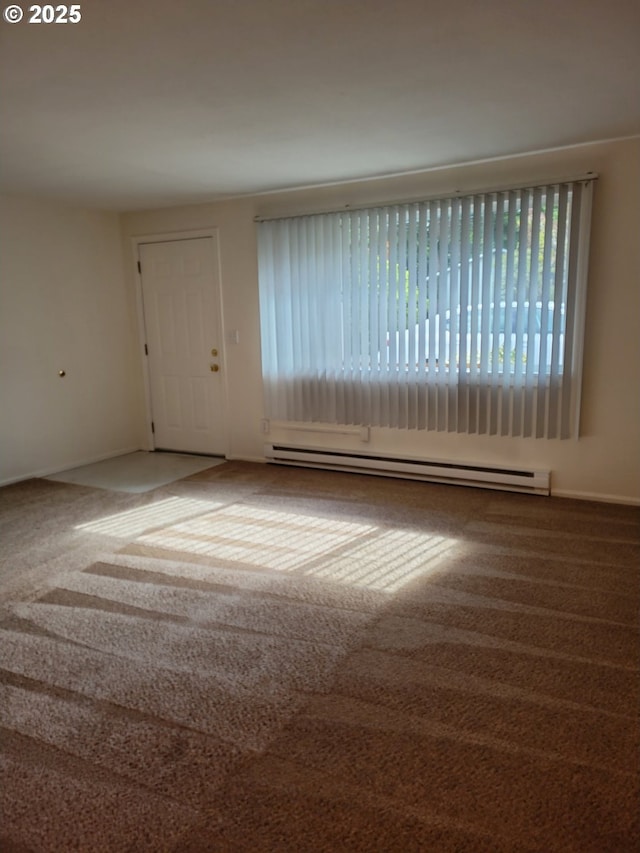 carpeted spare room featuring a baseboard heating unit