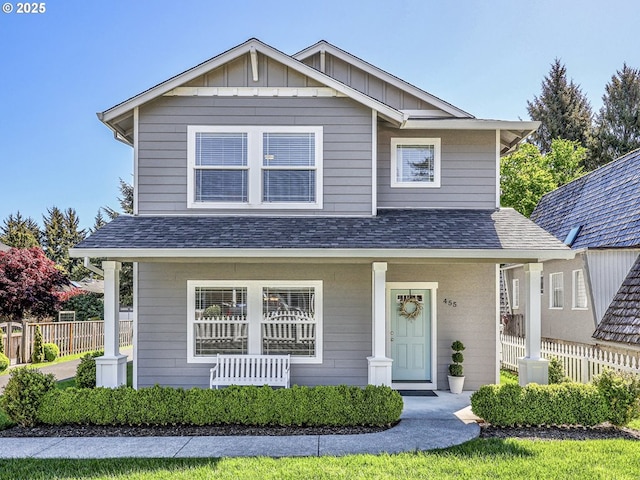 view of front of property featuring covered porch, fence, and a shingled roof