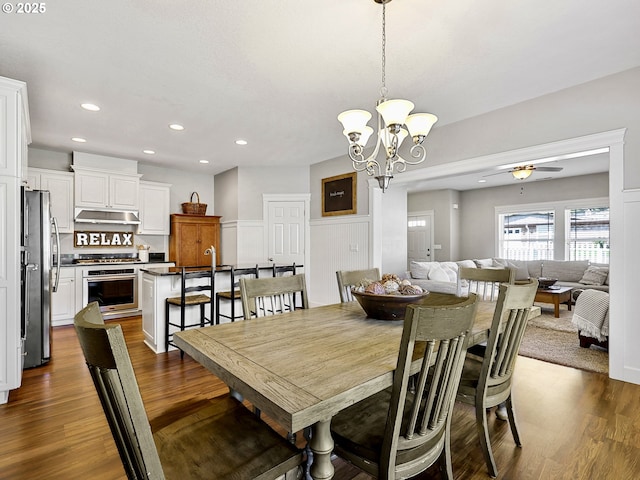 dining room with recessed lighting, dark wood-type flooring, a chandelier, wainscoting, and ceiling fan