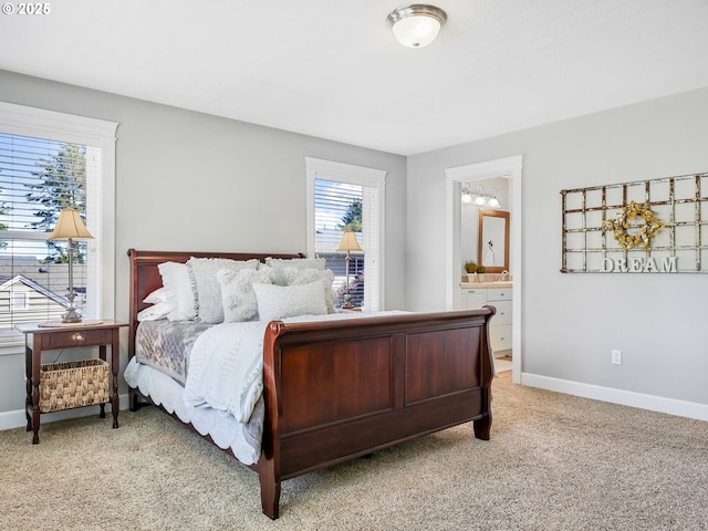 bedroom featuring light colored carpet, baseboards, and ensuite bath