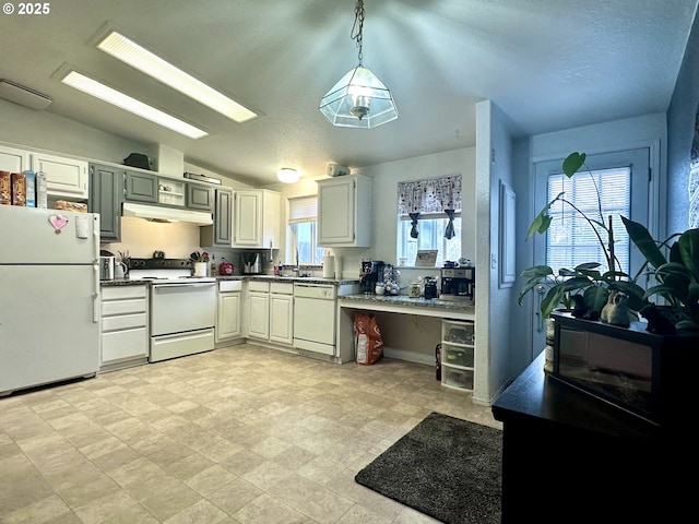 5510 E St, Springfield, OR 97478 - kitchen with white appliances, under cabinet range hood, dark countertops, lofted ceiling, and pendant lighting