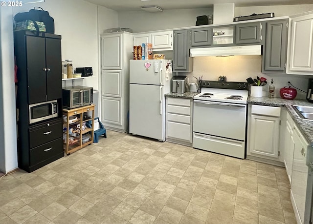 5510 E St, Springfield, OR 97478 - kitchen with white appliances, under cabinet range hood, stone finish flooring, and white cabinetry