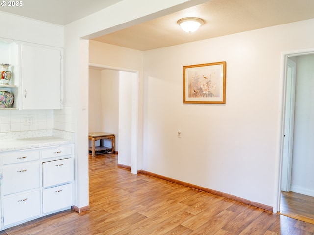 kitchen featuring backsplash, white cabinets, and light wood-type flooring