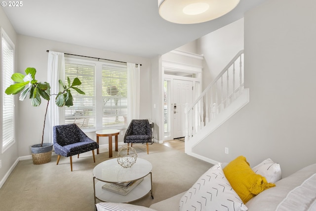 living room with stairs, baseboards, and light carpet
