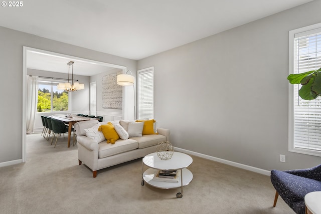 living area with light colored carpet, baseboards, and a notable chandelier