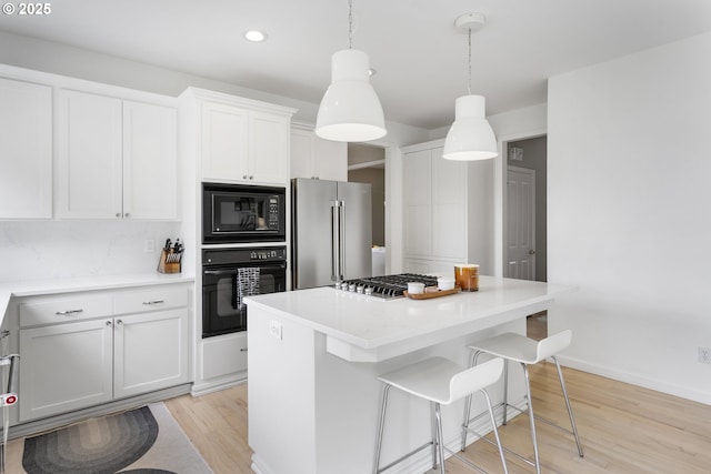 21890 SW 106th Ave, Tualatin, OR 97062 - kitchen featuring black appliances, light wood-style flooring, a center island, white cabinetry, and recessed lighting