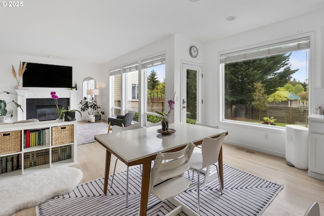 21890 SW 106th Ave, Tualatin, OR 97062 - dining room with light wood-style flooring, a tiled fireplace, and baseboards