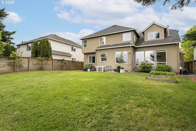 back of house with a lawn, a fenced backyard, and roof with shingles