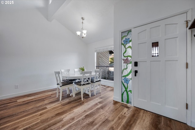 dining area featuring beam ceiling, a notable chandelier, wood finished floors, high vaulted ceiling, and baseboards