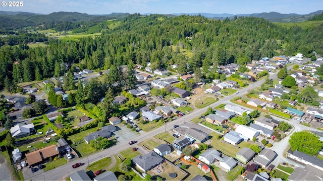 1636 Maple St, Myrtle Point, OR 97458 - aerial view of property and surrounding area featuring a forest, a mountain backdrop, and nearby suburban area