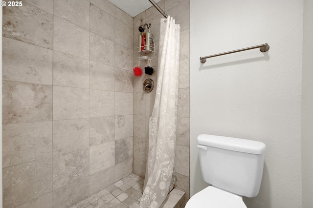 bathroom featuring toilet and a tile shower