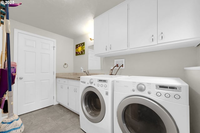 washroom featuring a sink, cabinet space, and washing machine and clothes dryer