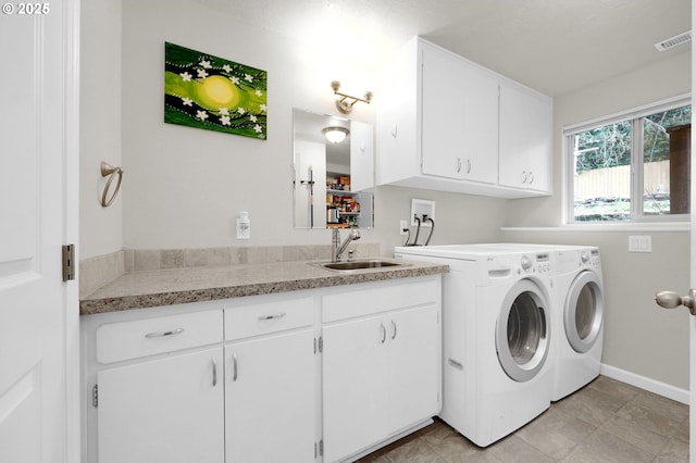 clothes washing area featuring visible vents, baseboards, washing machine and dryer, cabinet space, and a sink