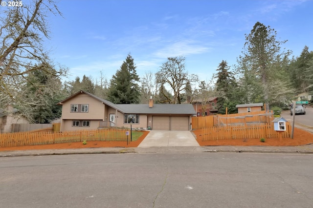 view of front of home featuring concrete driveway, an attached garage, a fenced front yard, and a chimney