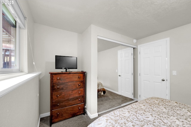 carpeted bedroom featuring baseboards, a closet, and a textured ceiling