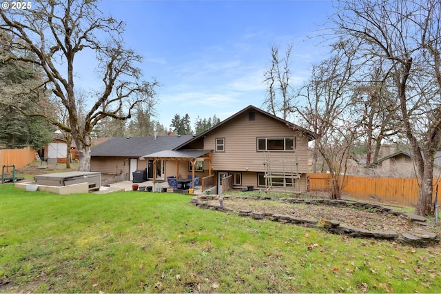 rear view of property with a yard, a fenced backyard, a chimney, and a hot tub