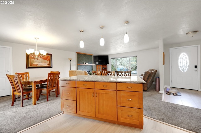 kitchen with light carpet, open floor plan, and hanging light fixtures