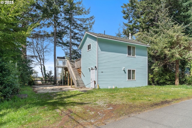 view of property exterior with a yard, a wooden deck, a patio area, and stairway