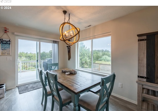 dining space with baseboards, wood finished floors, visible vents, and a notable chandelier