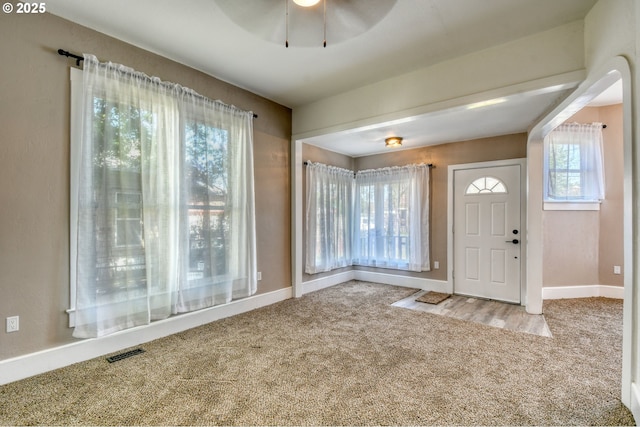 carpeted foyer entrance featuring visible vents, a ceiling fan, and baseboards