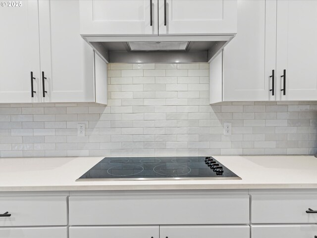 kitchen with light countertops, white cabinets, backsplash, and black electric cooktop