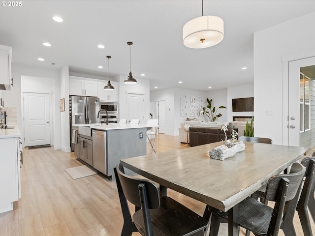 dining space with sink and light wood-type flooring