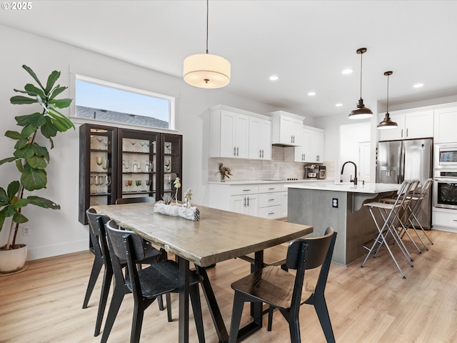 dining space with baseboards, light wood finished floors, and recessed lighting