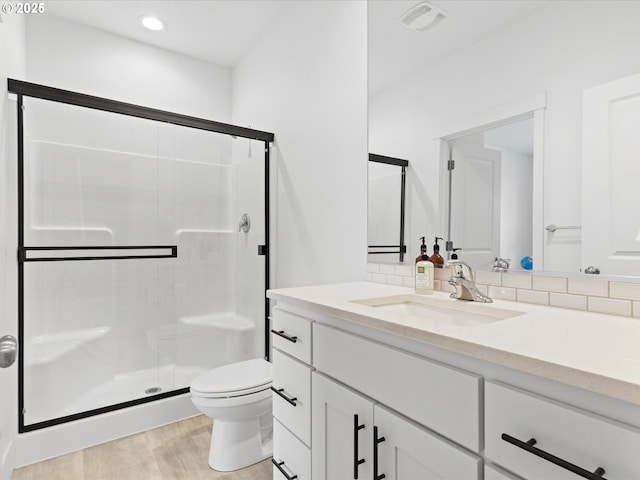 bathroom with toilet, an enclosed shower, vanity, hardwood / wood-style floors, and backsplash