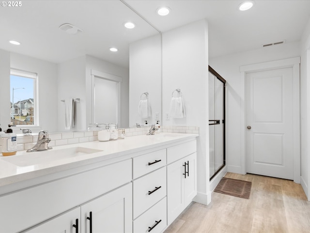 bathroom with vanity, hardwood / wood-style floors, decorative backsplash, and an enclosed shower