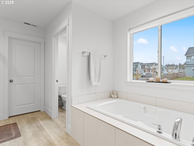 bathroom featuring hardwood / wood-style flooring, a bathing tub, and toilet