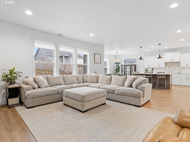 living room with light wood-type flooring, visible vents, and recessed lighting