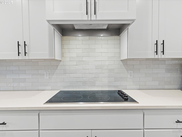 kitchen featuring black electric stovetop, backsplash, white cabinets, and extractor fan