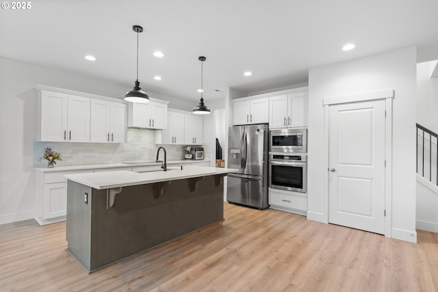 kitchen with a sink, white cabinets, light countertops, appliances with stainless steel finishes, and tasteful backsplash