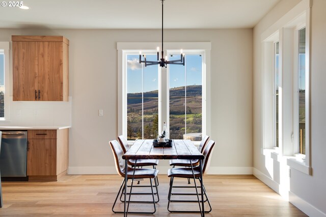 kitchen with stainless steel appliances, sink, wall chimney exhaust hood, light brown cabinets, and hanging light fixtures