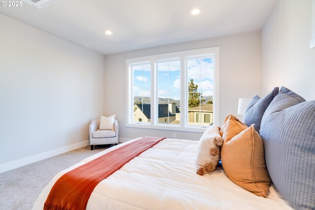 bedroom featuring a barn door, light carpet, and ensuite bath