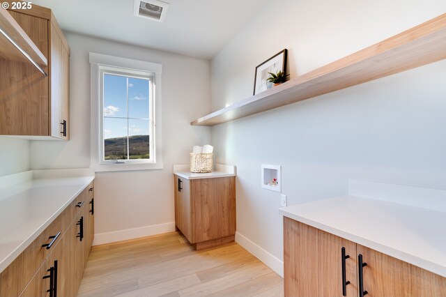 laundry area with light hardwood / wood-style flooring, cabinets, and hookup for a washing machine