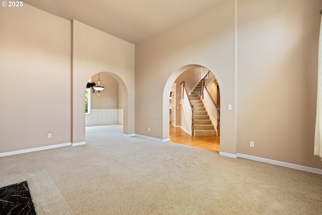 2103 N Teakwood St, Canby, OR 97013 - spare room with carpet, arched walkways, a towering ceiling, stairs, and a chandelier