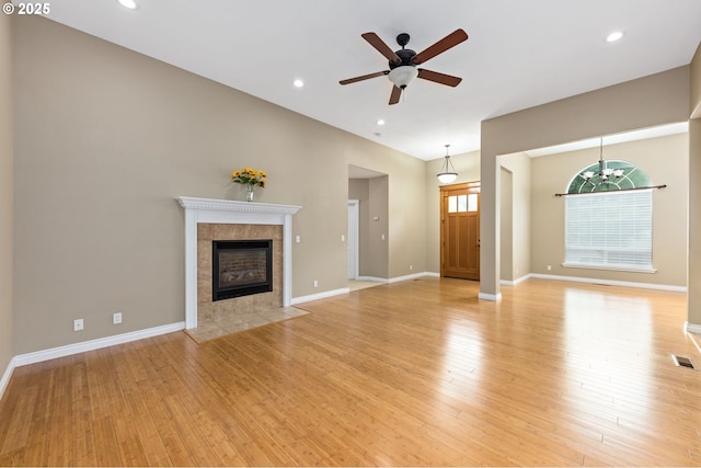 115 Duane Ct, Myrtle Creek, OR 97457 - unfurnished living room featuring light wood-type flooring, a tiled fireplace, a ceiling fan, baseboards, and recessed lighting