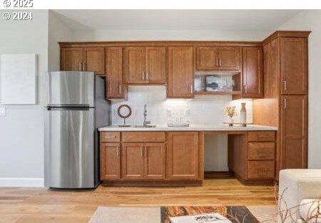 kitchen featuring stainless steel refrigerator, sink, and light hardwood / wood-style flooring